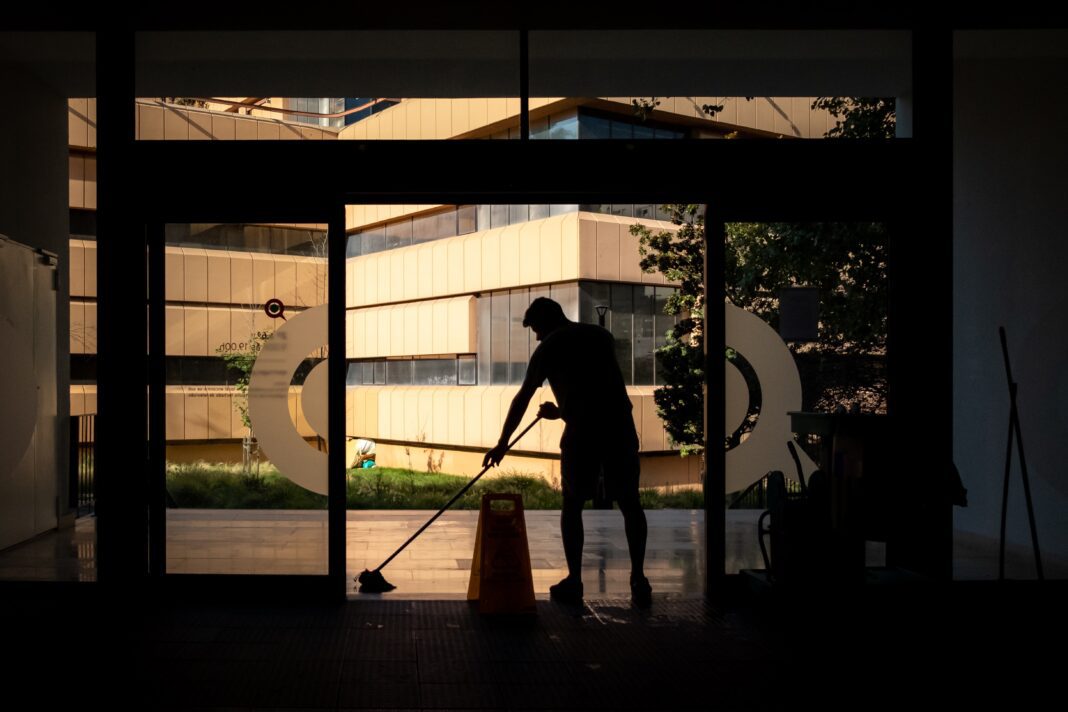 Trabajador limpiando la entrada de unas oficinas