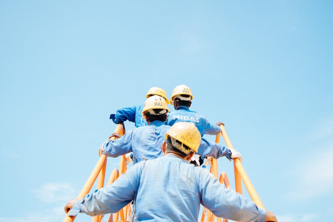 Trabajadores con casco amarillo subiendo una escalera